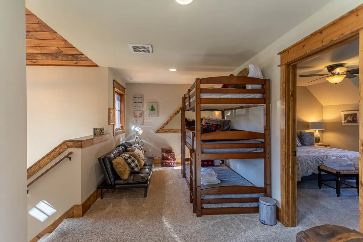 A charming loft area with triple bunk beds, an inviting seating nook, and decorative wall art. The arrangement encourages group activities such as bedtime storytelling or board games, while the soft colors and lighting evoke warmth and comfort.