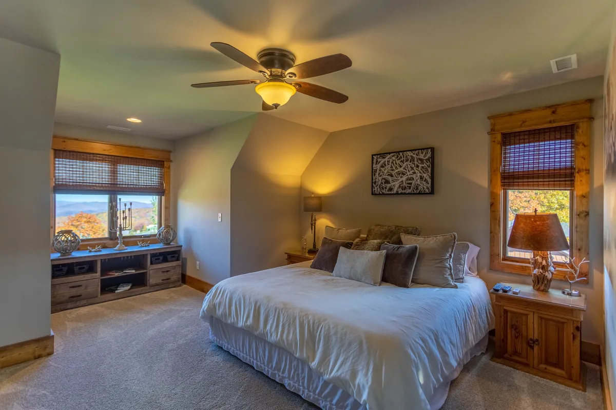 A tranquil bedroom with a plush bed positioned near a window, allowing for the enjoyment of sunrise or mountain views. The room features soft lighting, a nightstand, and tasteful artwork, creating a cozy and romantic ambiance.