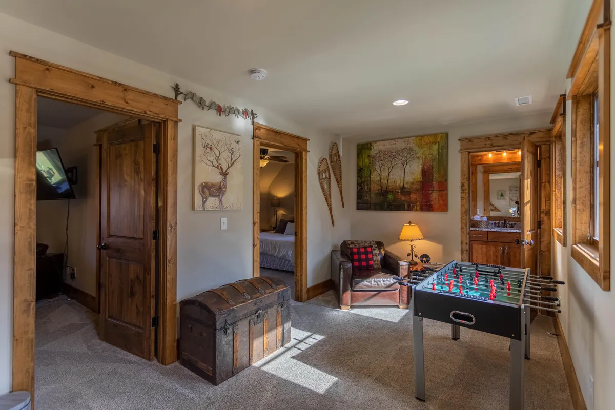 The image spotlights a foosball table set in a welcoming corner, paired with a wooden trunk, armchair, and artistic wall accents. The configuration suggests a dedicated game zone within the loft, perfect for friendly competitions or casual leisure.